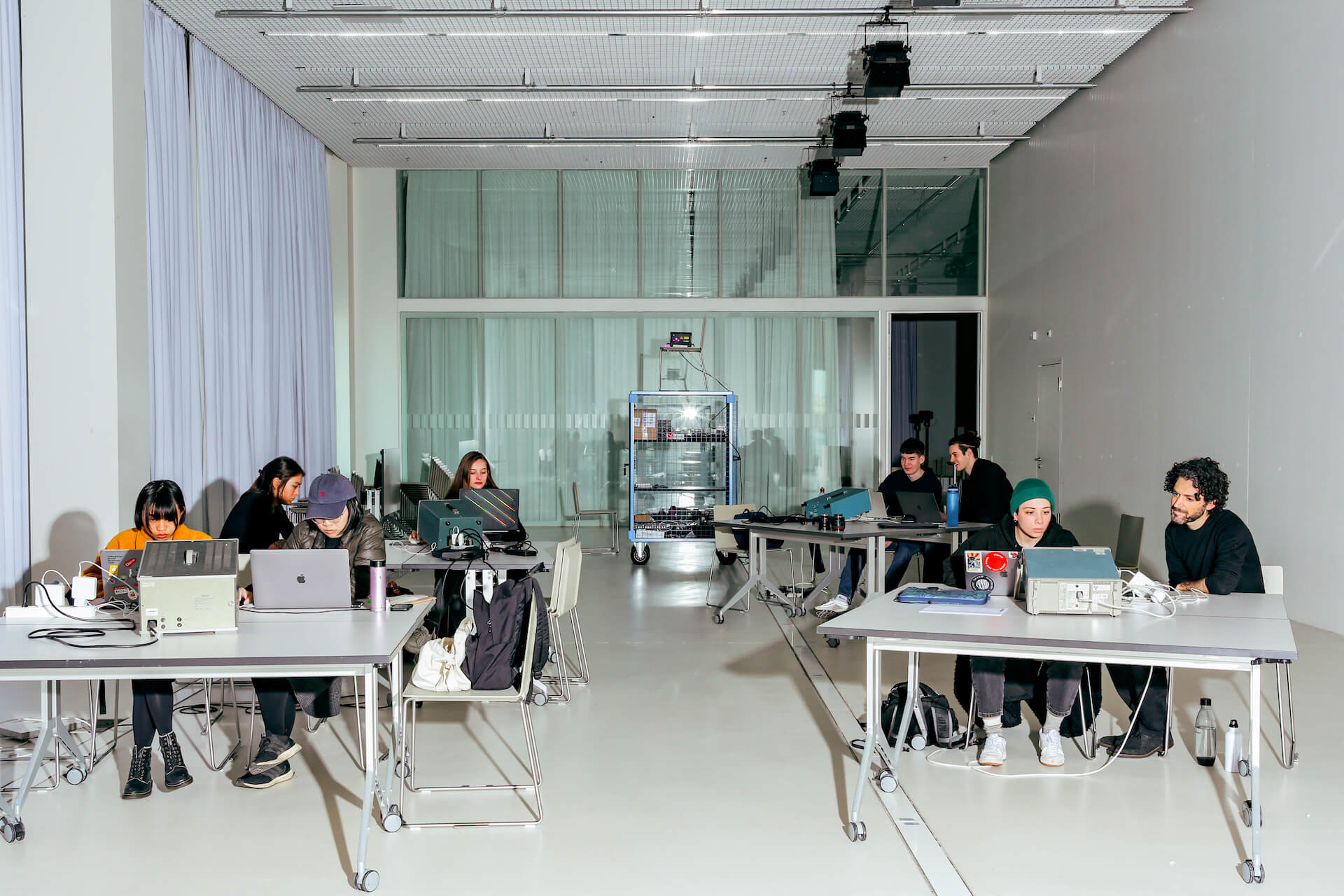 Verschiedene Gruppen Studierender sitzen je an einem Tisch und tauschen sich aus