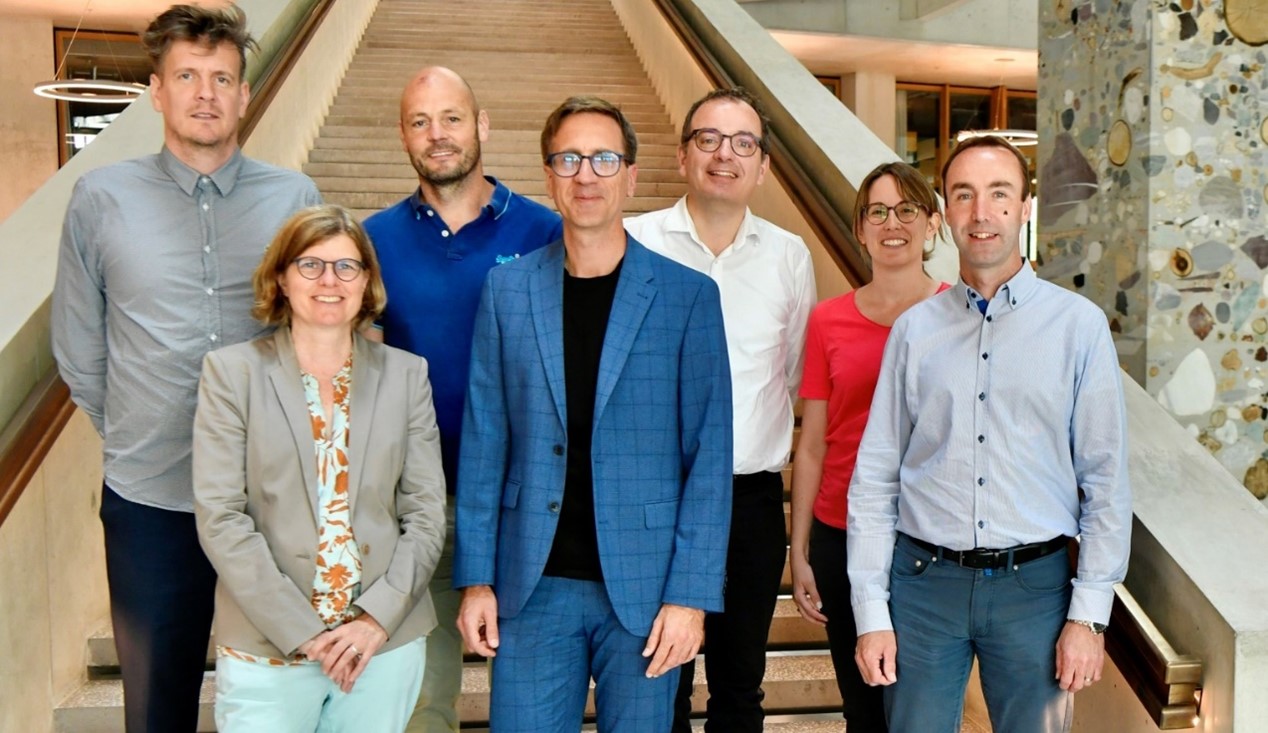 Die Gruppenleitenden und die Leiterin Services stehen vor einer Treppe im Foyer der FHNW Campus Muttenz
