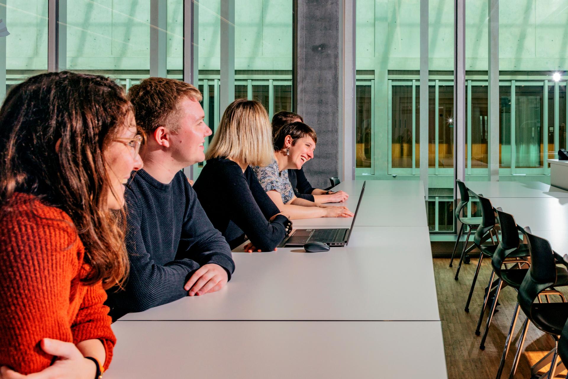 Studierende sitzen in einer Reihe an Tischen im Unterrichtsraum