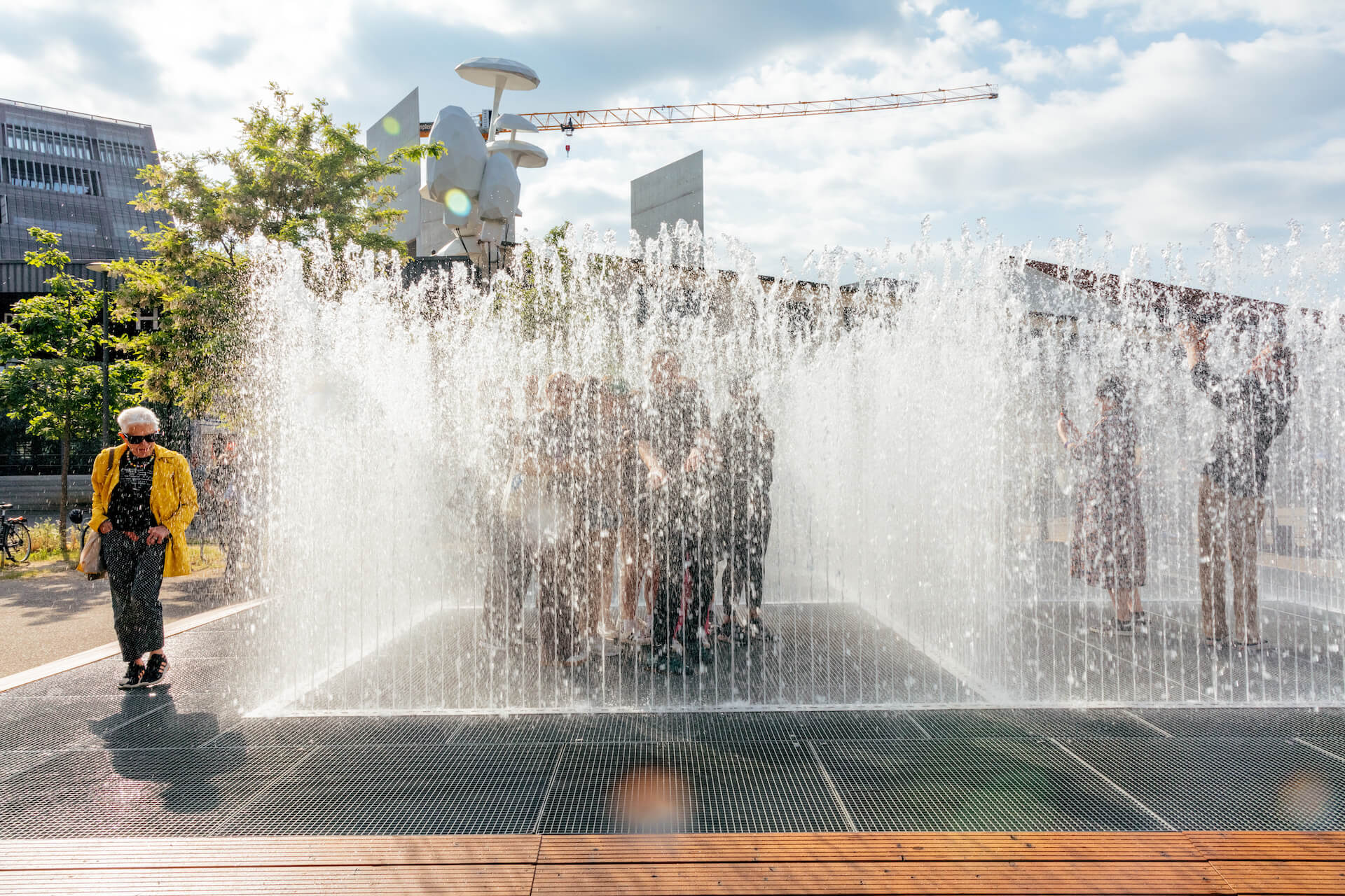 Personen stehen im Wasserpavillon Appearing Rooms. Durch quadratisch angeordnete Wasserfontänen entsteht ein temporärer Raum