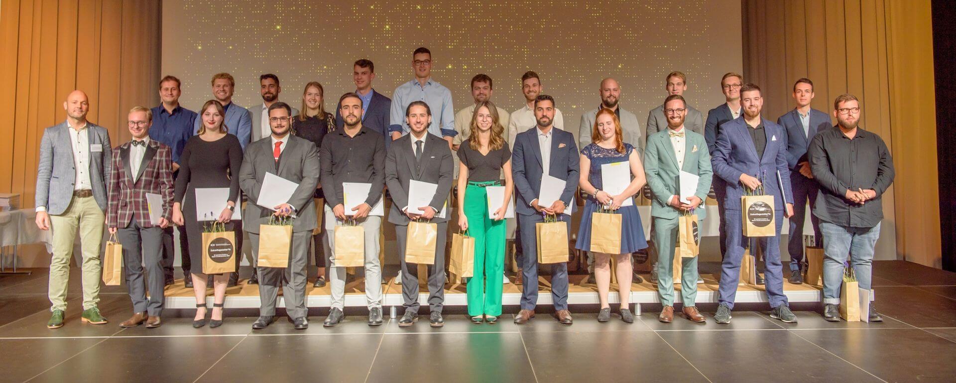 Die Absolvent*innen stehen auf der Bühne und halten ihre Diplome.