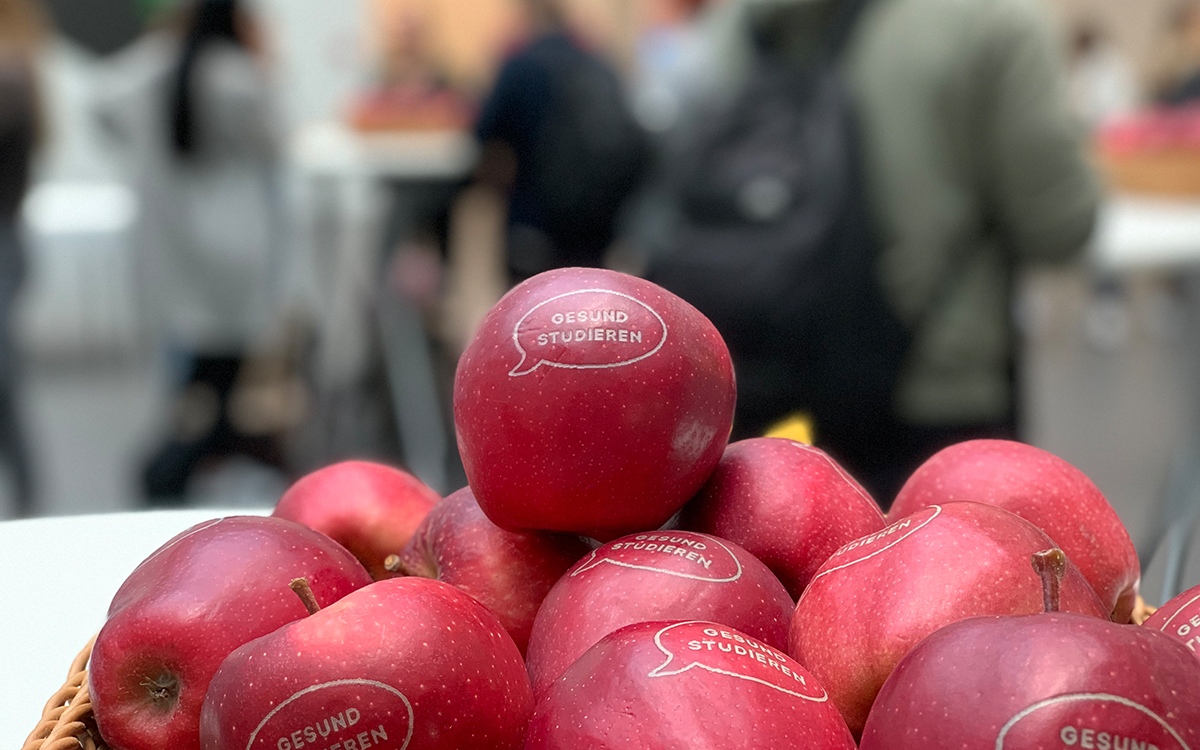 Mehrere rote Äpfel aufgetürmt auf einem Tisch. 