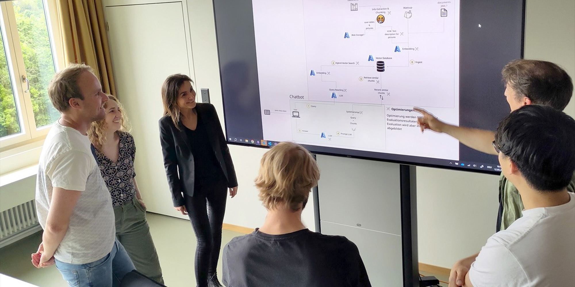 Projektmitarbeiter besprechen vor Bildschirm Aufbau eines Chatbots