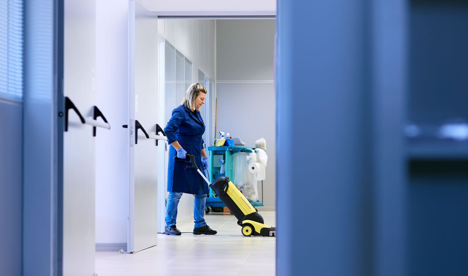 Eine Putzfrau putzt mit einem Staubsauger ein Büro.