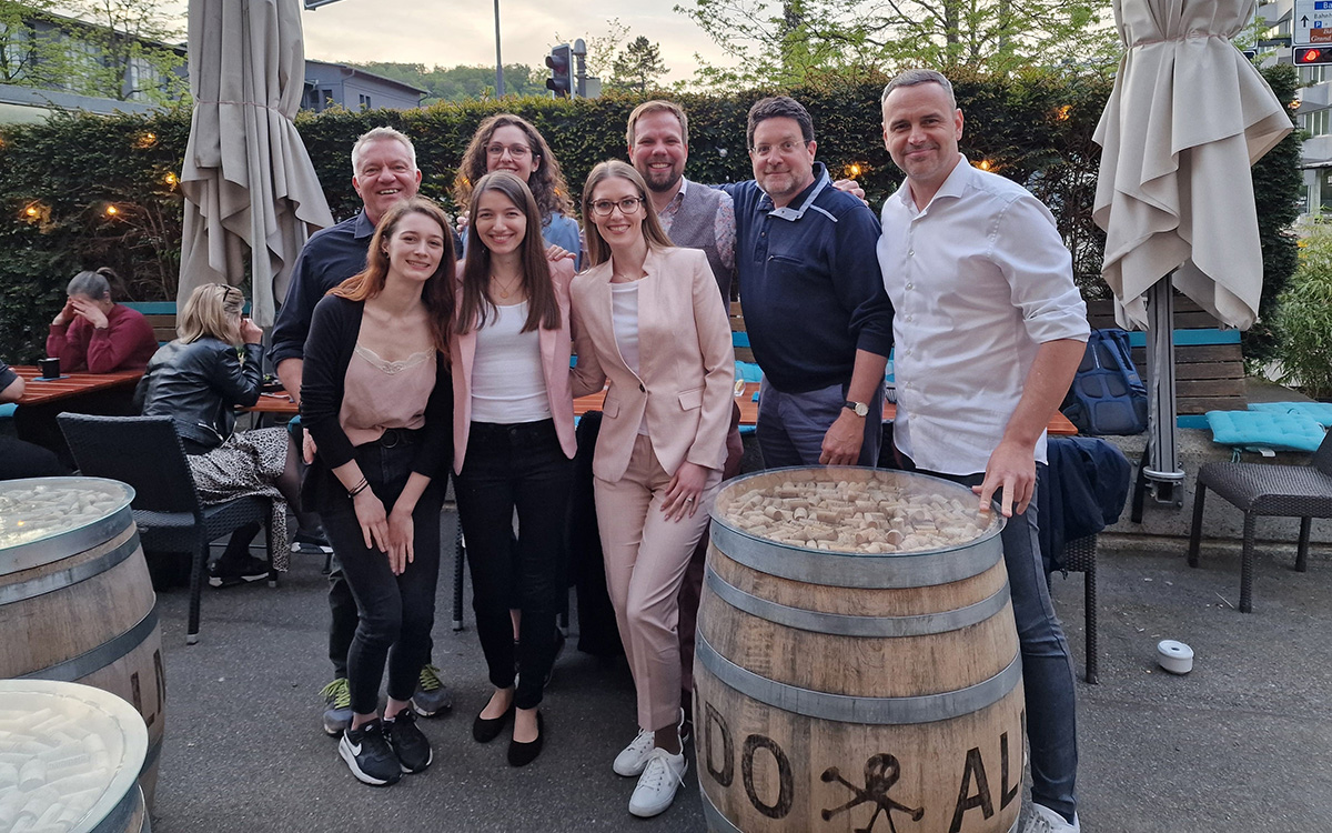 Gruppenfoto der Studierendengruppe mit dem Praxispartner. Sie stehen draussen im Garten einer Bar. 