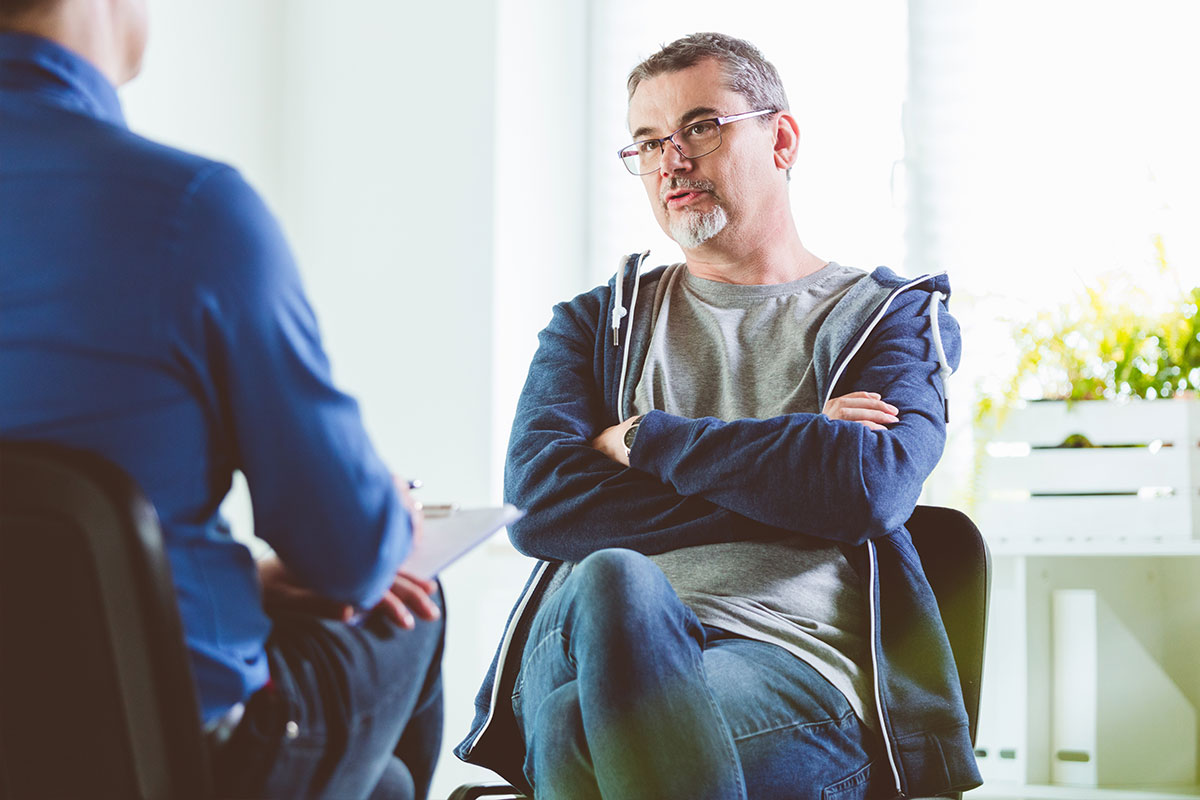 Zwei Männer sitzen gegenüber voneinander, einer ist Berater, der andere Klient.