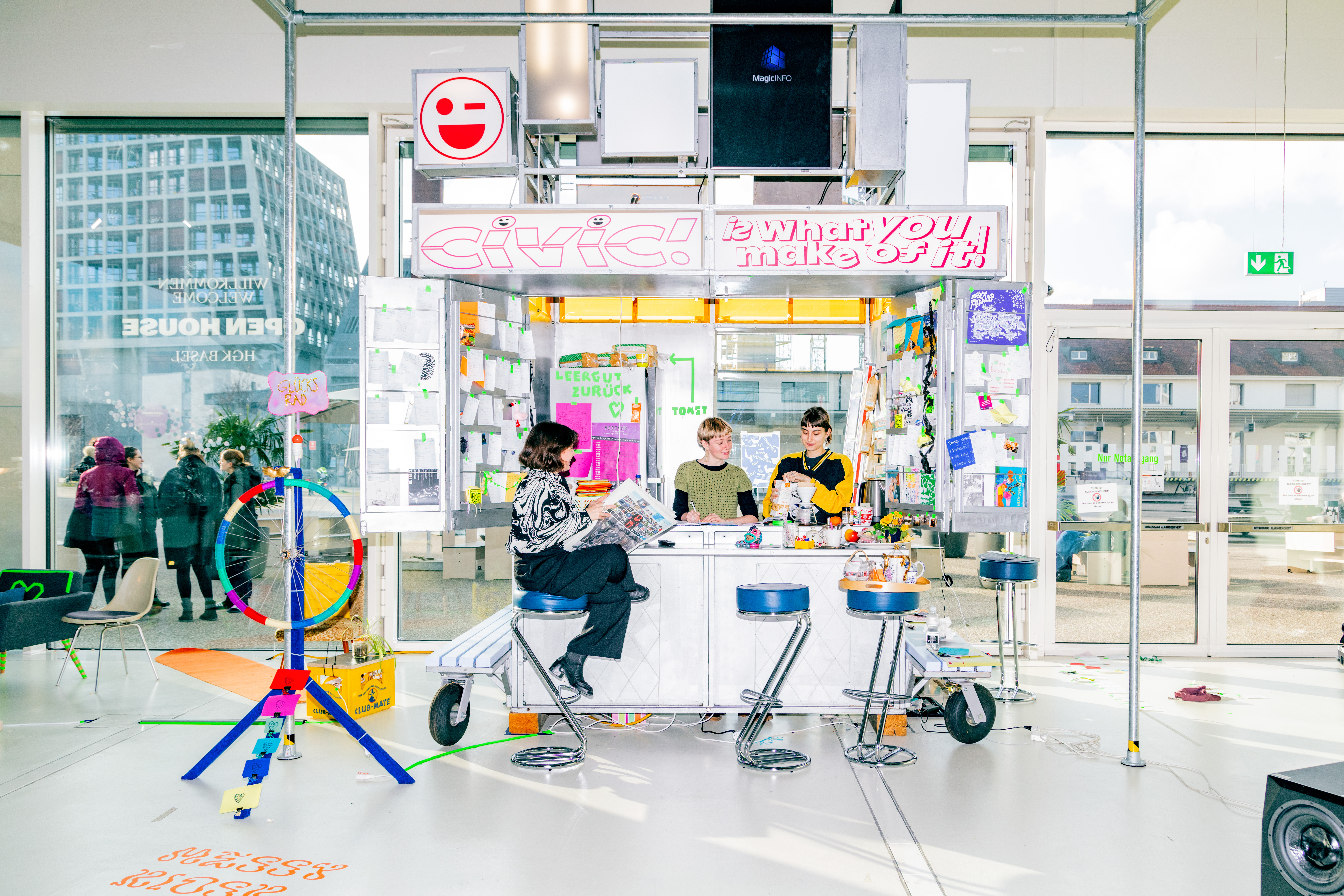 Studierende der HGK Basel FHNW sitzen im Foyer in einer Art Kiosk und lesen ein Magazin