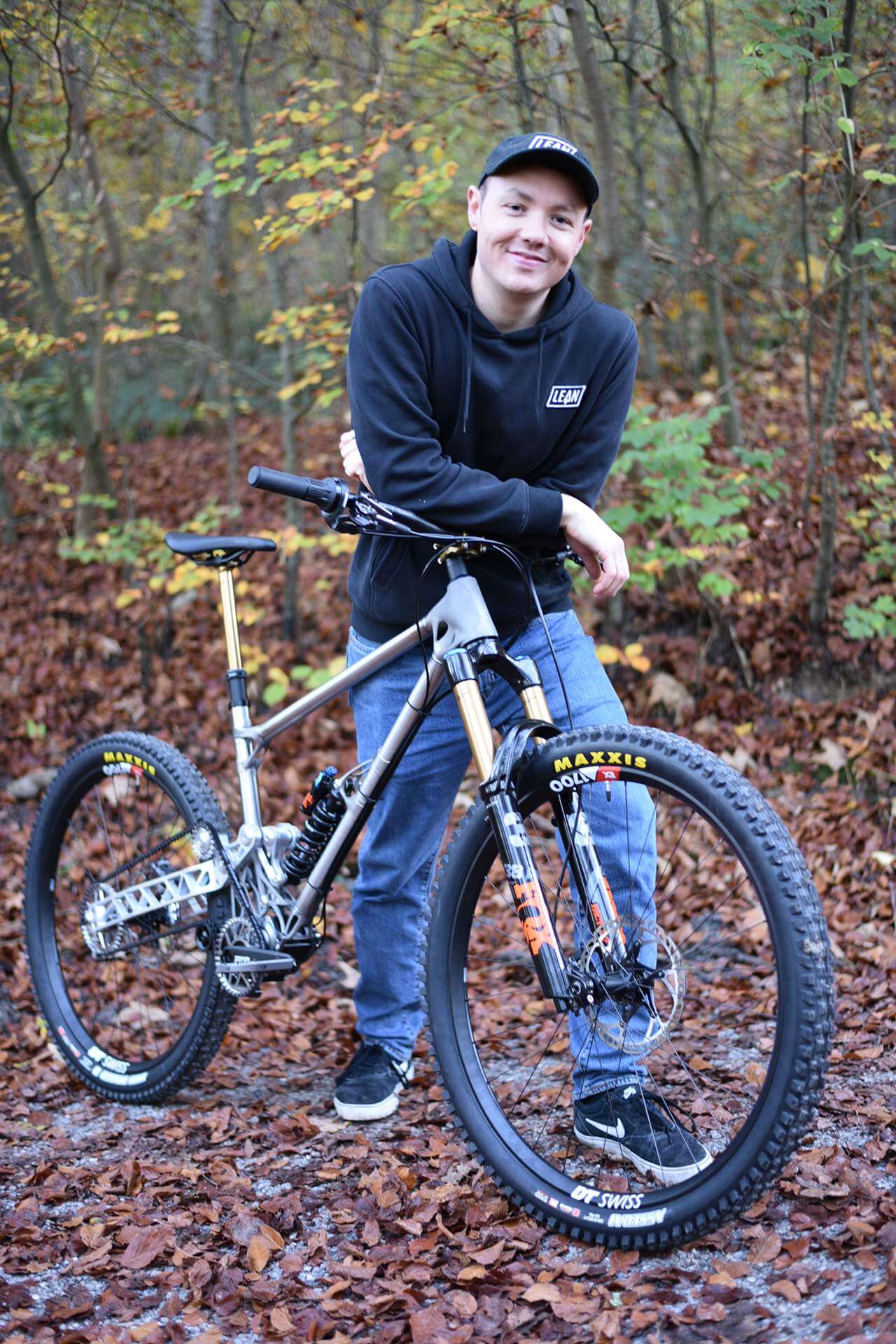 Luca Bühlmann lehnt auf dem Lenker seines Enduro-Bikes. Er steht im Wald.